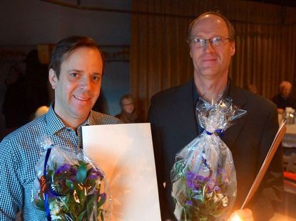 Två glada pristagare med diplom och blommor