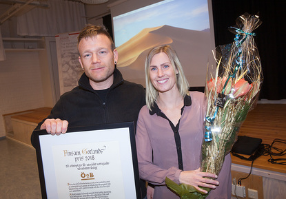 Två glada pristagare av Hederspriset står med diplom och blommor