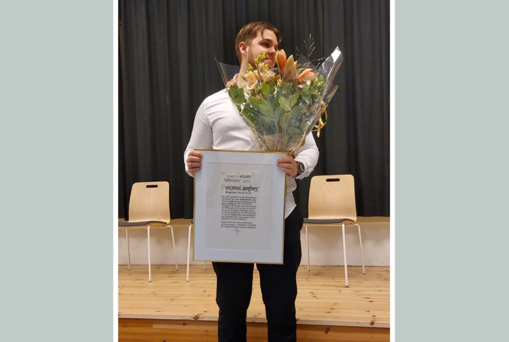 Benjamin, som har vit tröja och svarta byxor håller i sitt diplom och sina blommor